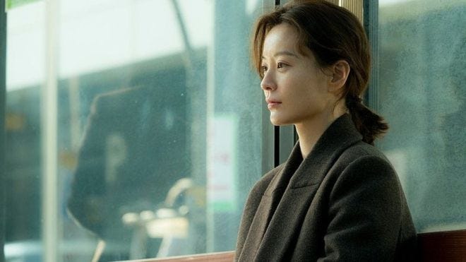 Kim Ji-young at a bus stop, looking pensive