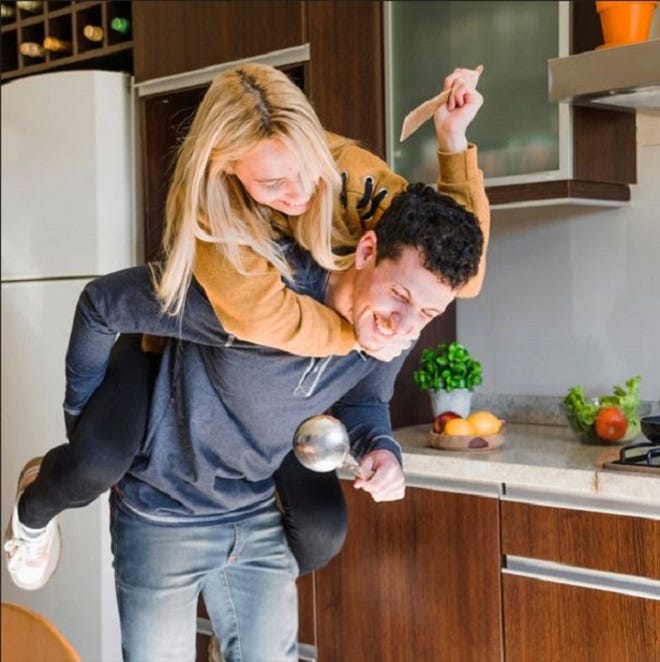A couple being playful in the kitchen and laughing