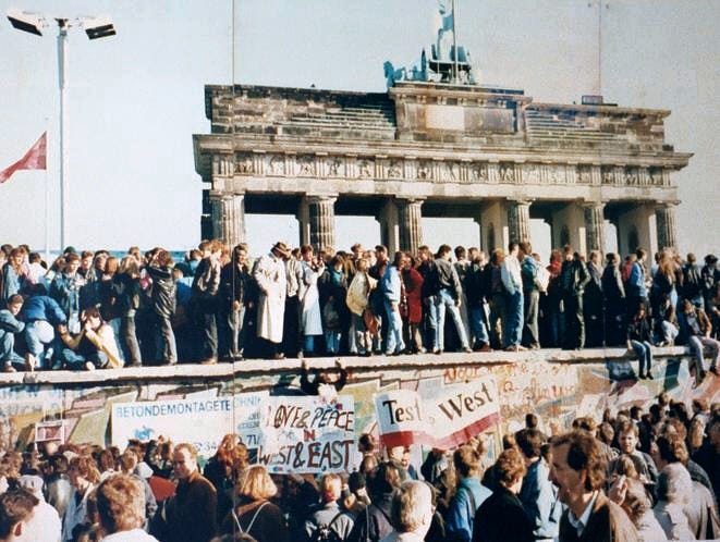 A photo of West and East Germans gathering at the Berlin Wall days before its fall in front of the Brandenburg Gate, 1989.