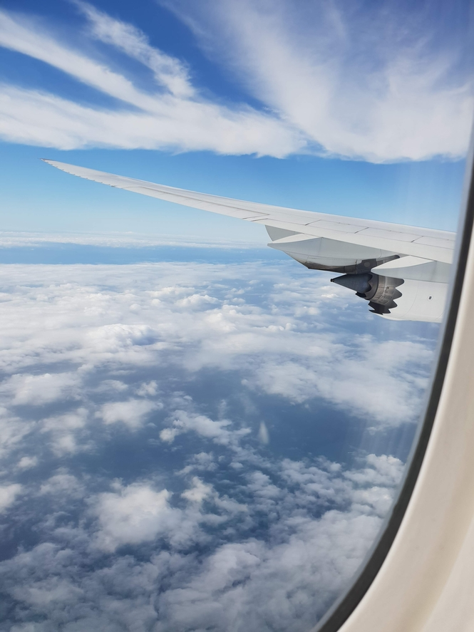 Image taken from my seat on the airplane, airplane wing, blue sky and clouds.