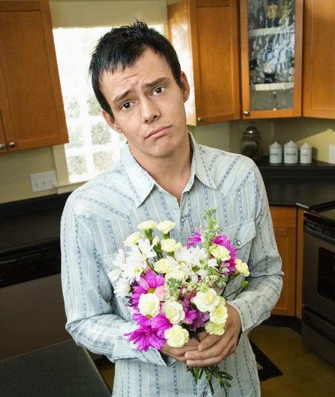 A sad-looking guy tries to apologize with flowers.