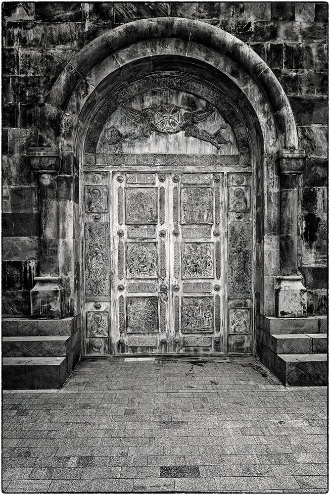 Black and white image of a door carved with religious imagery at the Dariali Monastery Complex in Georgia.