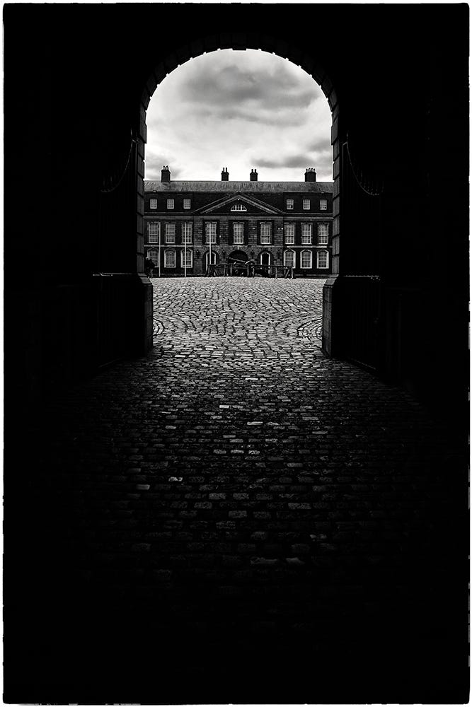 Black and white image of Dublin Castle viewed through a stone arch