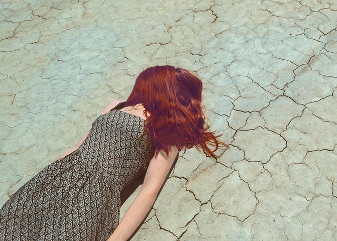 Woman with red hair laying on the ground.