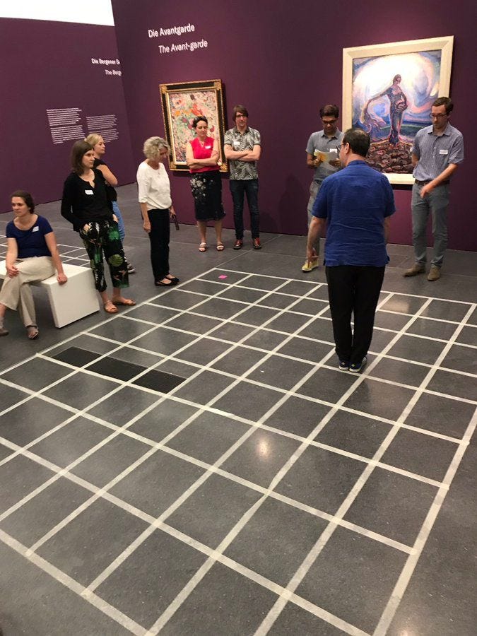 A man walking on a floor divided into squares by masking tape