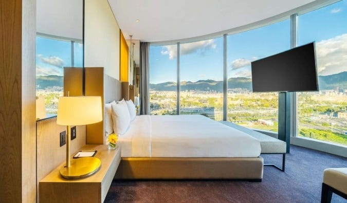 A large guest room at the Grand Hyatt in Bogotá, Colombia, with wrap-around floor-to-ceiling windows with views over the city and mountains
