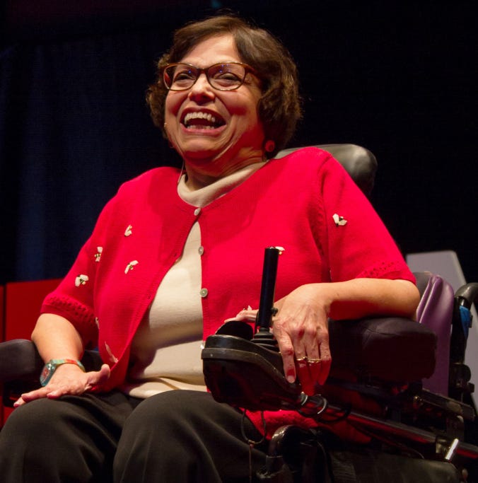 Photo of Judy Heumann in her powerchair, laughing