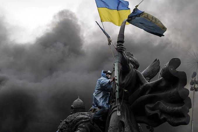 A protester sits on a monument in Kyiv during clashes with riot police in February 2014