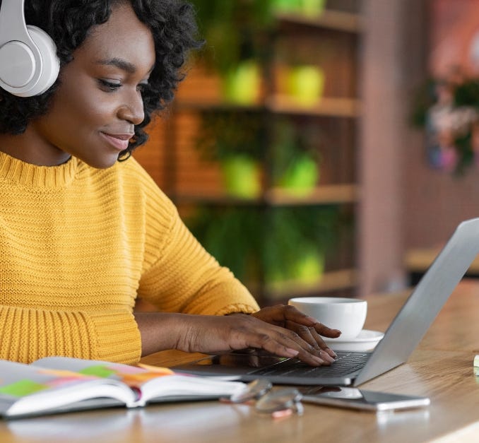 Freelancer/Consultant focused woman with headphones using laptop in a cozy setting.