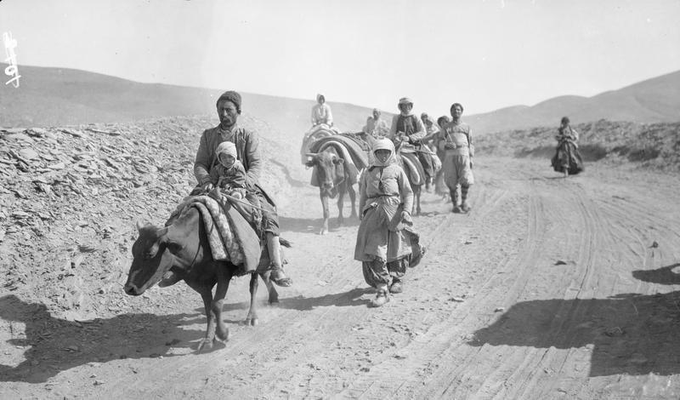 Fotografia em preto e branco de assírios cruzando a passagem de Asadabad em direção a Baqubah, em 1918. Eles estão atravessando o deserto montados nos animais.