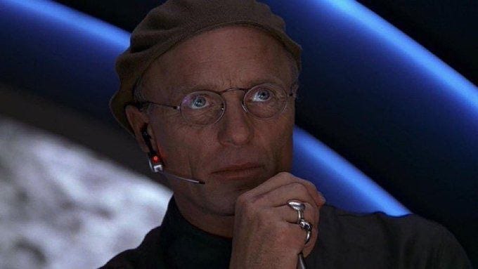 Still image of a man in glasses and a beret looking serious, used as a conspiracy-style reaction meme.