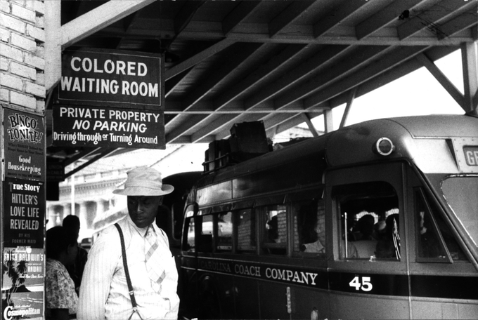 Fotografia colorida da estação de ônibus em Durham, Carolina do Norte, maio de 1940: a placa indica o local das pessoas de cor. À esquerda, um anúncio fala sobre Hitler.