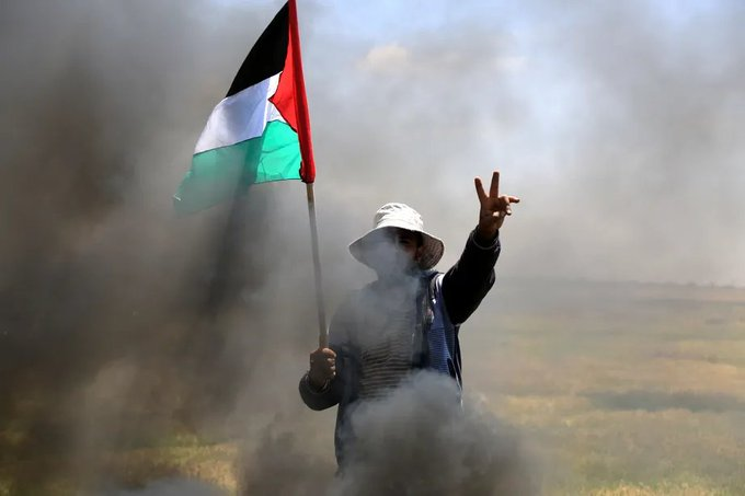 Um manifestante palestino faz um sinal em V durante uma manifestação exigindo a reconstrução das áreas destruídas nos ataques israelenses.