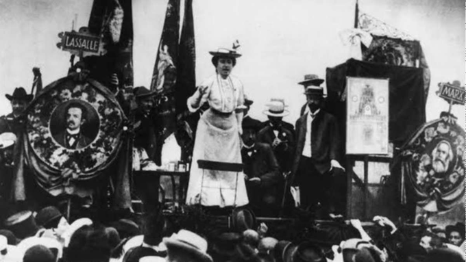 Rosa Luxemburgo, com vestes brancas, discursando na 2ª Internacional para uma multidão, em 1907 na cidade de Sttugart, Alemanha.