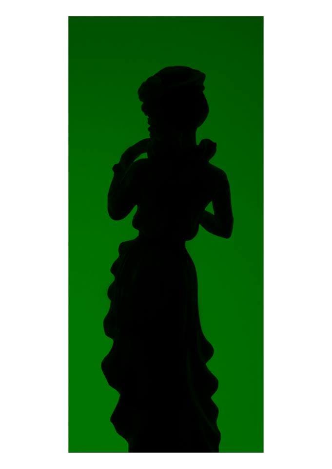 A portrait silhouette of a porcelian doll on a dark green background