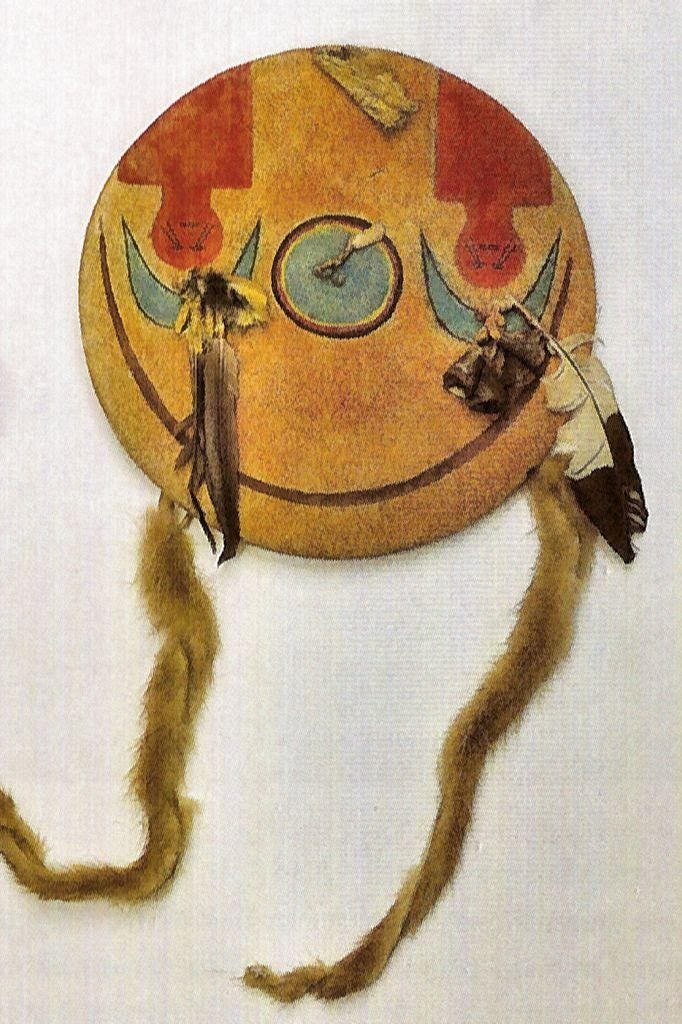 A multi-colored shield with some feathers and other ornaments.