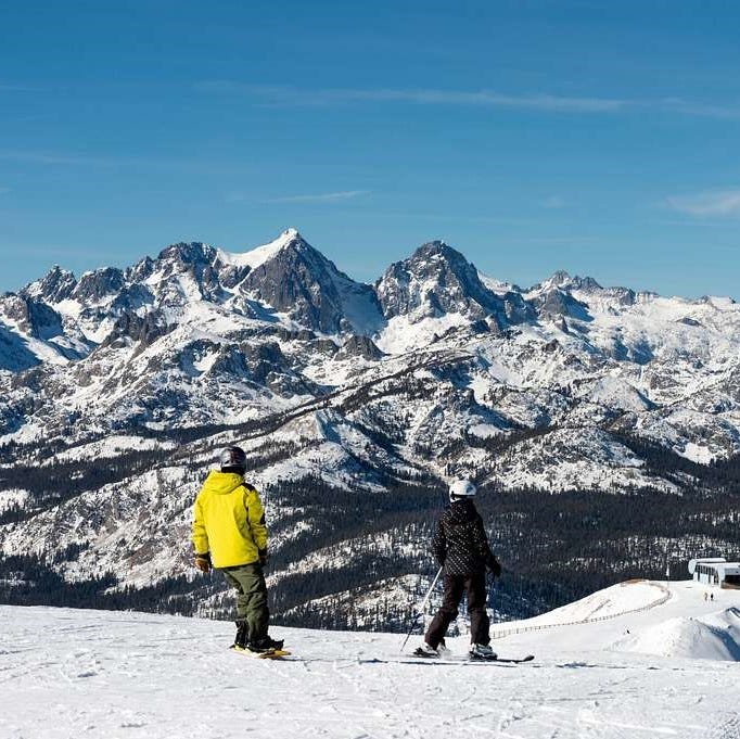 A snowboarder and a skier on top of Mammoth Lakes, California mountain resort.