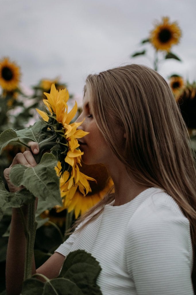Woman smells a sunflower as she copes with divorce.
