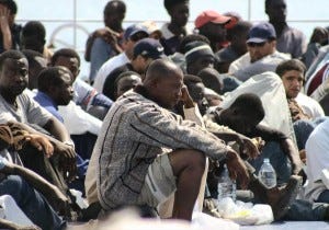 Asylum seekers, part of the some 350 Africans who arrived 14 and 15 June 2003 on the island of Lampedusa wait to betransferred by police to Agrigento, Lampedusa main city,16 June 2003. The xenophobic leader of Italy's Northern League and cabinet minister Umberto bossi suggested today using cannons to combat the growing problem of immigration, as the government prepares to implement more restrictive asylum policies. AFP PHOTO/ANSA/FRANCO LANNINO