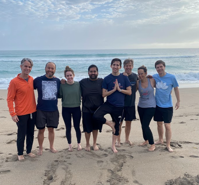 Doug stands with Aledade executives on a beach in Florida after a morning yoga session.