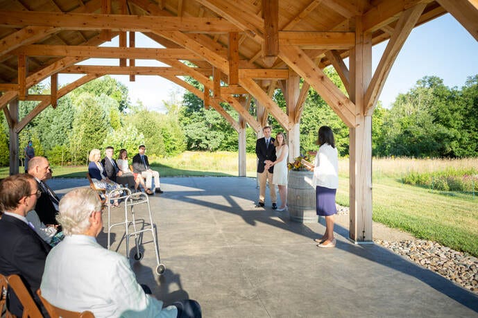 Bride and groom hold hands before their parents, grandparents and siblings, the only guests in attendance at a 2020 Covid Wedding.