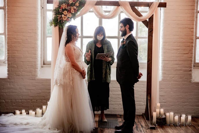 Wearing a mask with a bride and groom at a 2021 ceremony that was postponed from a 2020 Covid Wedding.