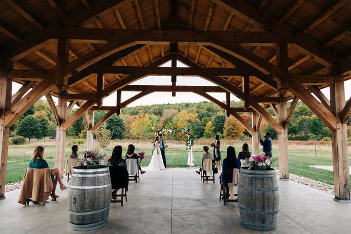 Bride and groom stand before their guests at an outdoors, masked and socially distant 2020 Covid Wedding.