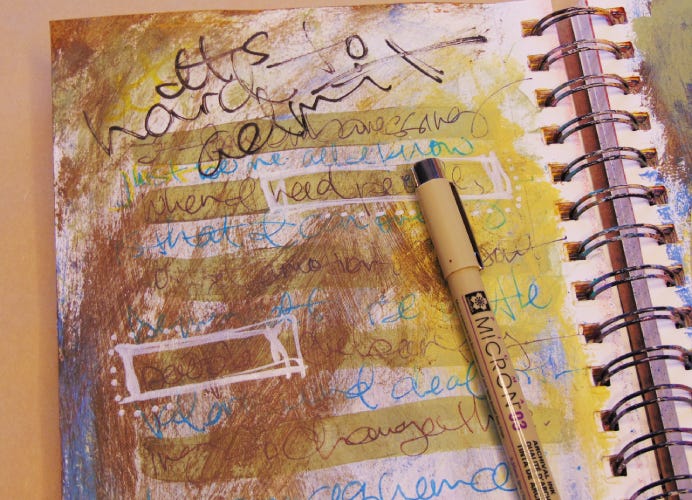 An art journal page with journaling in different colors, layered on top of one another