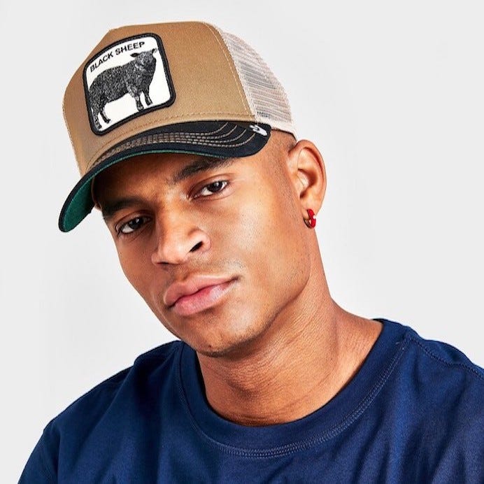 Black man with brown skin in a brown and black trucker hat with a Black sheep on the front.