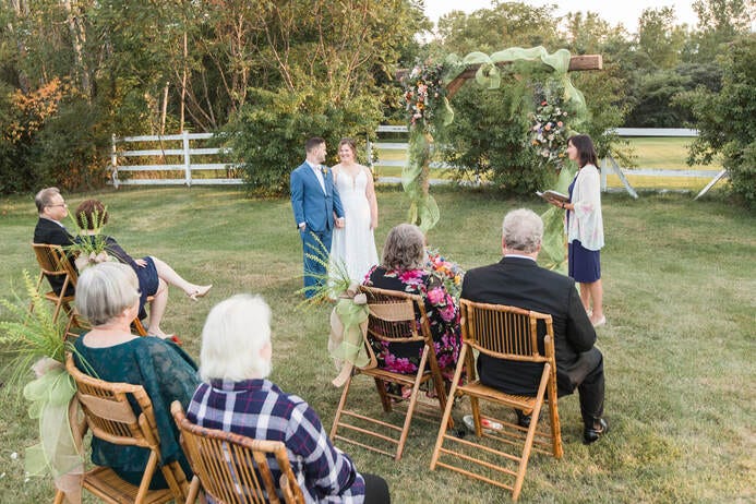 Bride and groom hold hands before their parents and grandparents, the only guests in attendance at a 2020 Covid Wedding.