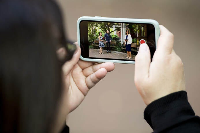 Wedding guests records a bride and groom on an iPhone at a 2020 Covid Wedding.