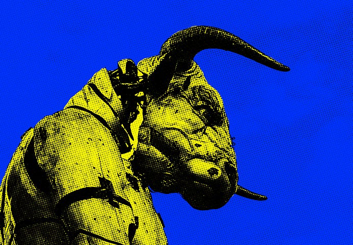 a picture of a statue of a demon- the background is bright blue and the statue has yellow hues