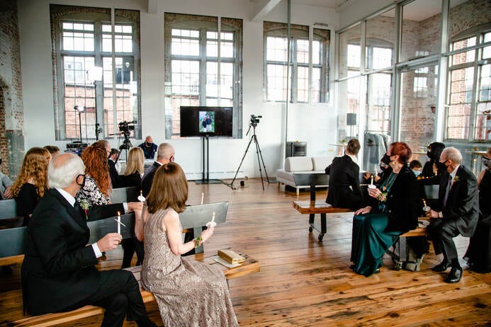 Large monitor displays guests attending via Zoom at a 2020 Covid Wedding.