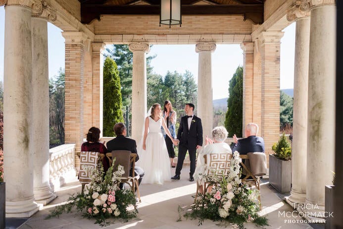 Bride and groom hold hands before their parents, the only guests in attendance at a 2020 Covid Wedding.