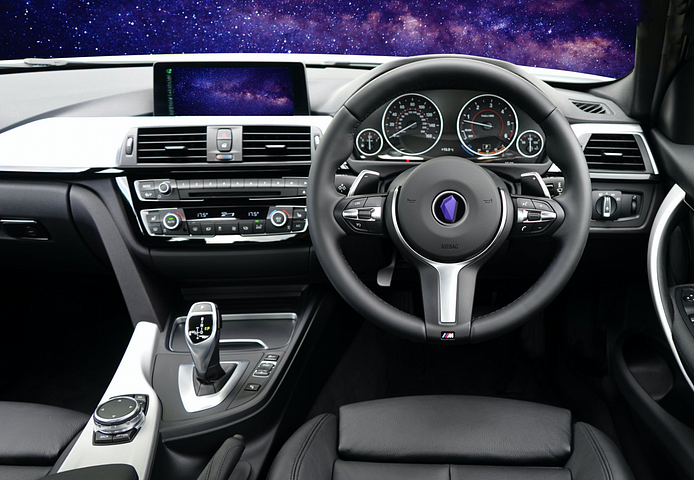 Car interior showing the steering wheel with Obsidian logo in the centre and dashboard. Purple outerspace star image shows in the windscreen and GPS.