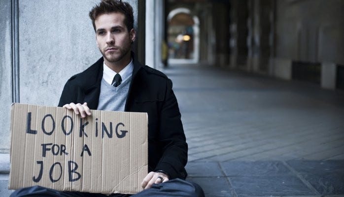 A white collar worker who’s lost his job holding a “looking for a job” sign
