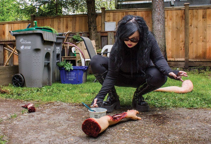 Woman puts fake blood on fake dismembered arm for photoshoot