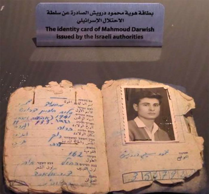 A imagem é uma foto da carteira de identidade de Mahmoud Darwish emitida pelas autoridades israelenses. O cartão contém informações manuscritas, como nome, data de nascimento, endereço e cor do cabelo.