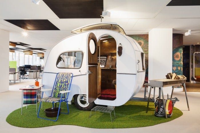 a caravan in an office with faux camping accessories around it.