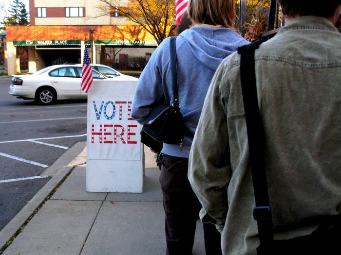 People standing in line on a sidewalk waiting to vote.