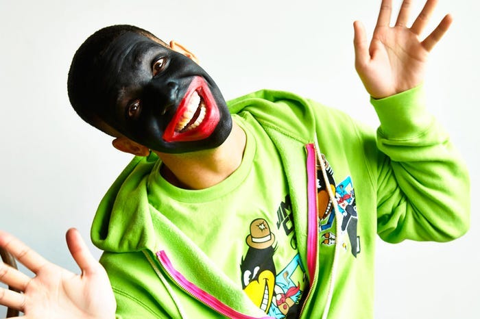 Photo of Aubrey ‘Drake’ Graham in blackface make-up as he smiles coonishly in bright green clothing.