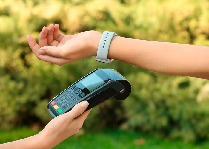 Braço com pulseira de pagamento efetuando transação em máquina de cartão