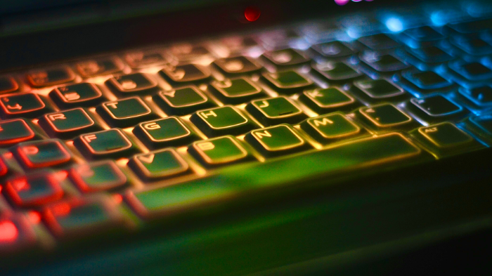 computer keyboard with green, blue, and red lights shining on it