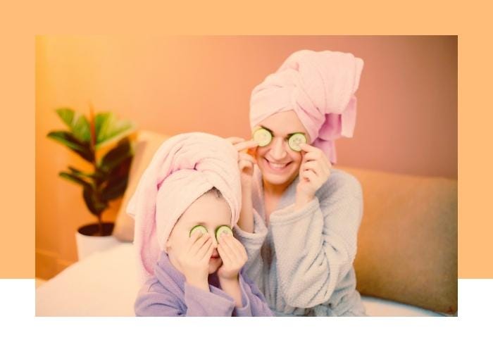 a mother and daughter putting cucumbers on their eyes, wearing bathrobes and towels