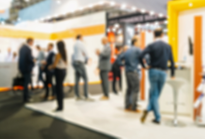 Blurry image showing people standing at a stand at an exhibition