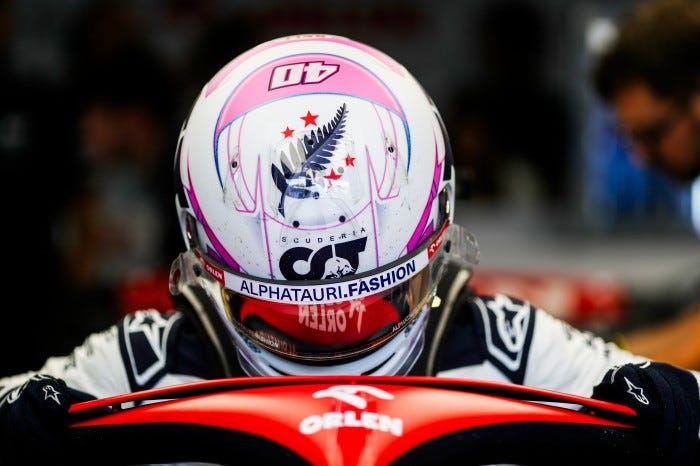 Liam getting into his car with his helmet on, prominently showing the fern and red stars of New Zealand on top of his helmet.