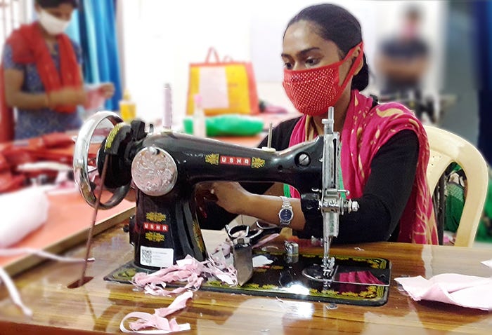 A young woman wearing a face mask uses a sewing machine.