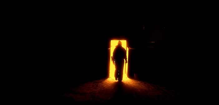 Person walking from darkness into doorway full of light