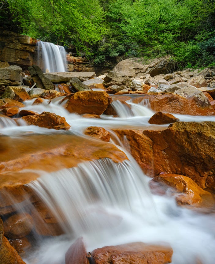 Sprawling waterfall flowing over and around orange boulders