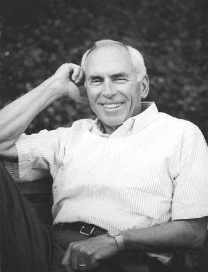 Photograph of a man (Roy Amara) in a white shirt sat on a chair looking relaxed.